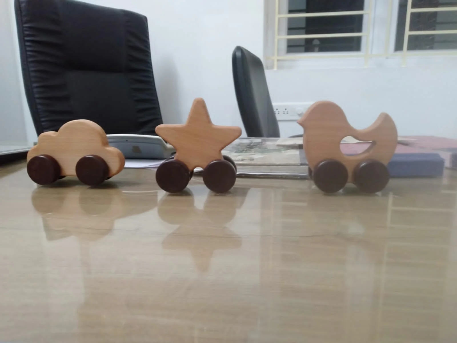 Drei kleine Holzspielzeuge mit Rädern: ein Auto, ein Stern und eine Ente